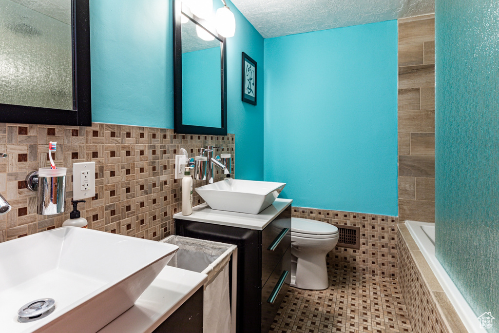 Bathroom with tile walls, vanity, tiled bath, and tiled shower