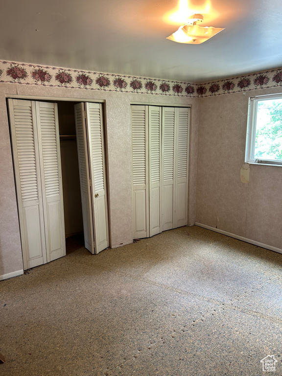 Unfurnished bedroom with multiple closets and carpet flooring