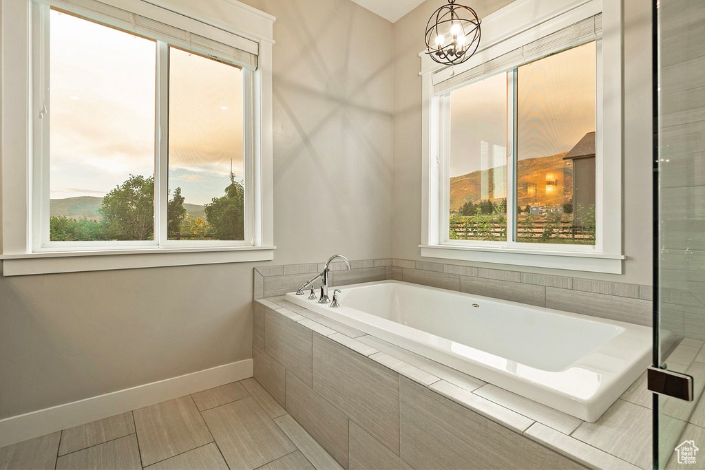 Bathroom with a garden tub, baseboards, and a chandelier