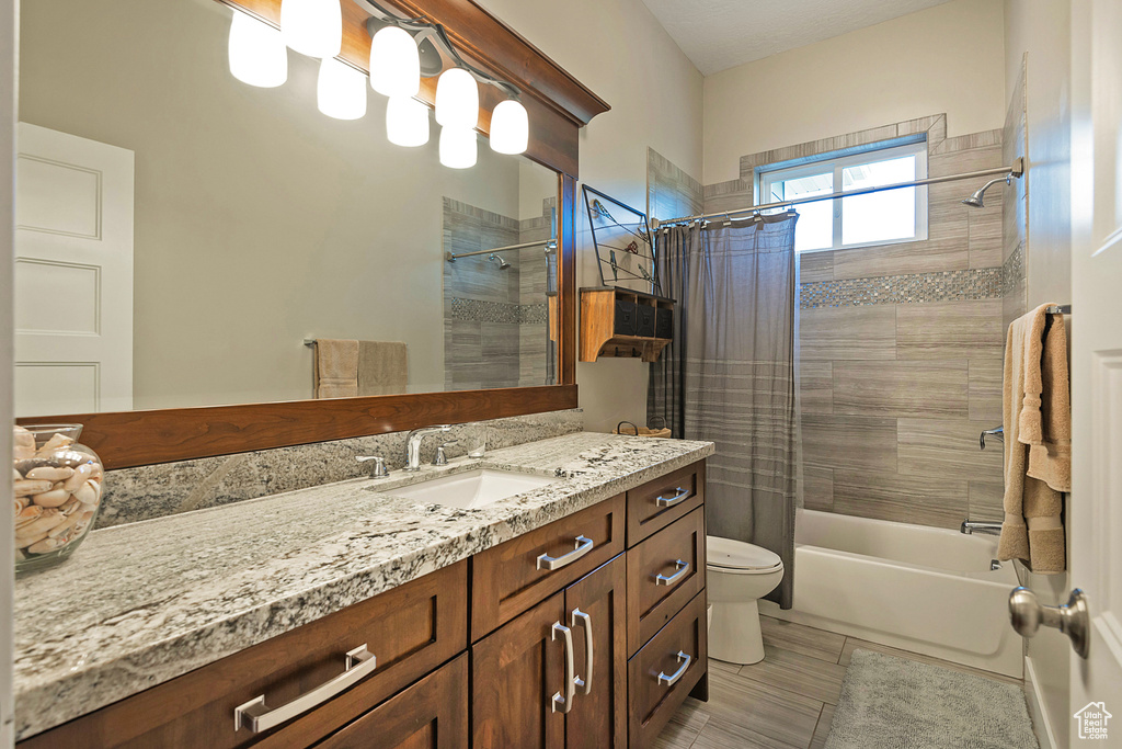 Bathroom featuring toilet, shower / bath combo with shower curtain, and vanity