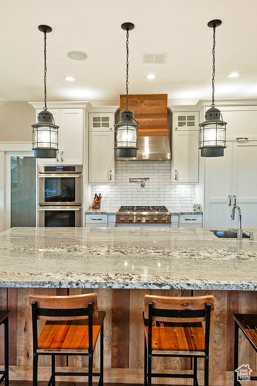 Kitchen with double oven, a sink, glass insert cabinets, decorative backsplash, and white cabinets