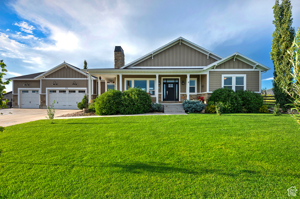 Craftsman house with board and batten siding, a chimney, driveway, and a front yard