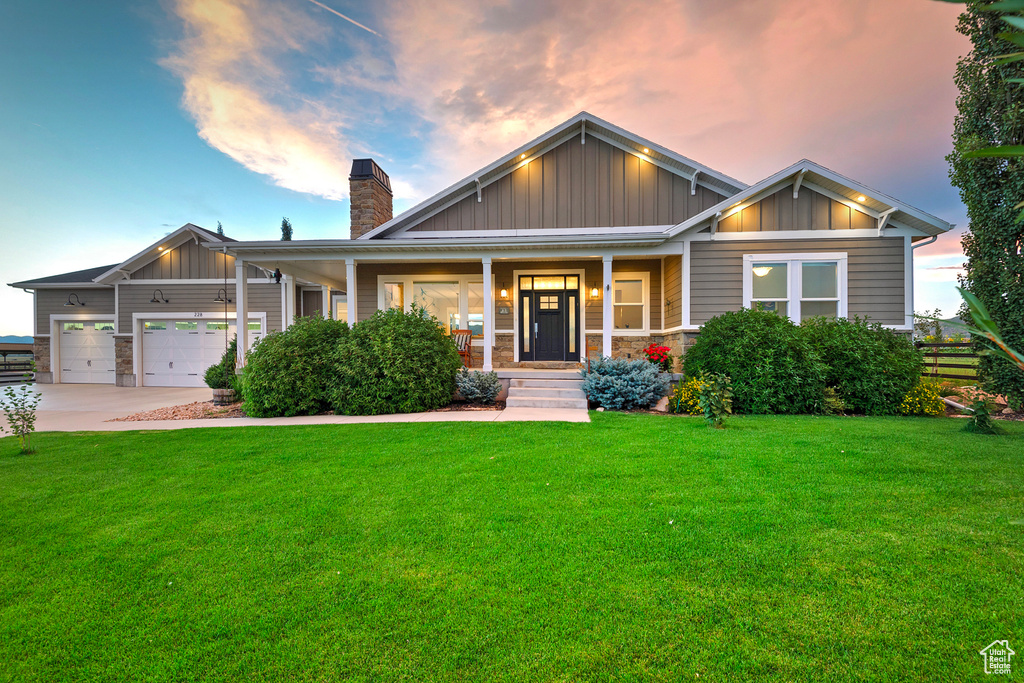 Craftsman-style house with board and batten siding, covered porch, a front lawn, and a chimney