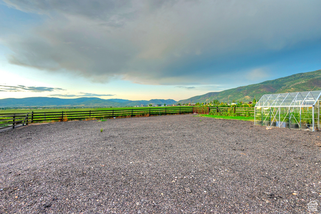 View of yard featuring a greenhouse, a mountain view, an enclosed riding area, an outbuilding, and a rural view