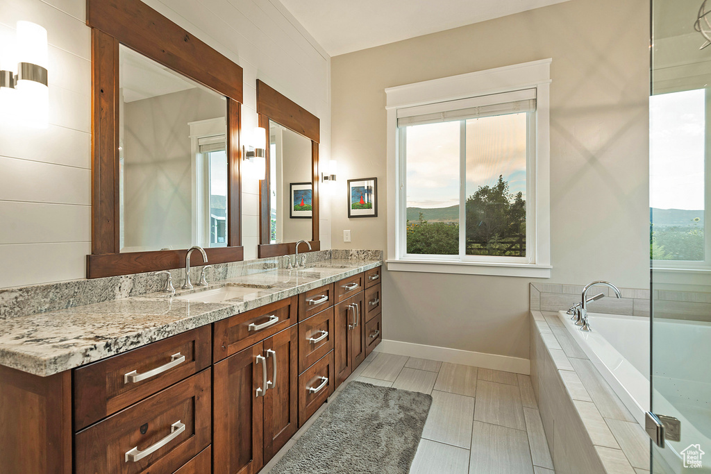 Full bath featuring double vanity, a garden tub, and baseboards