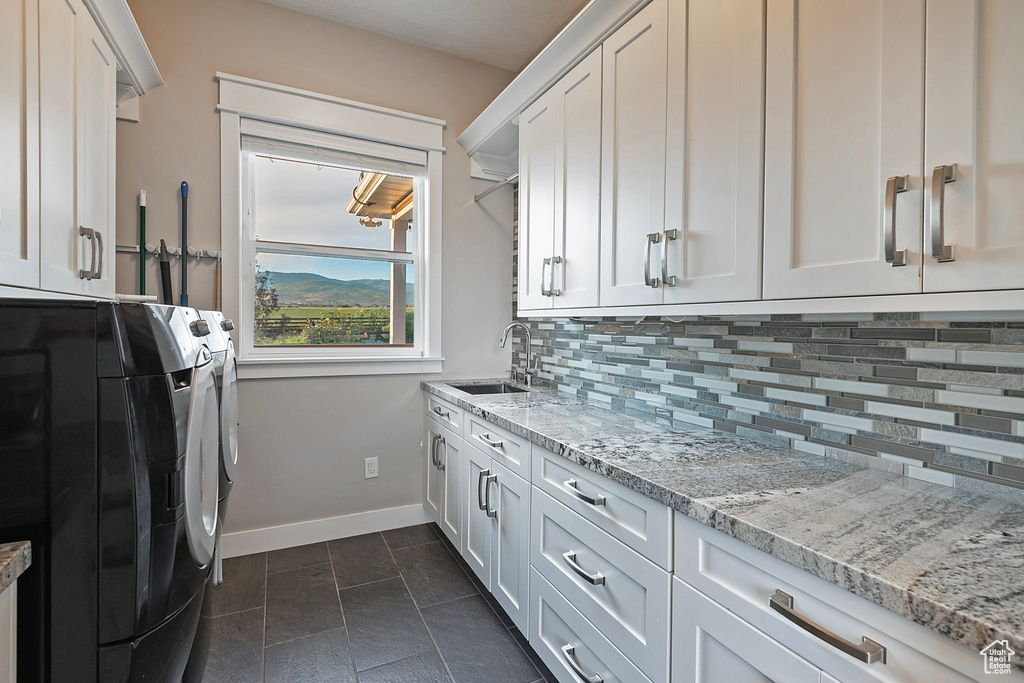 Washroom with washer and clothes dryer, cabinet space, and baseboards