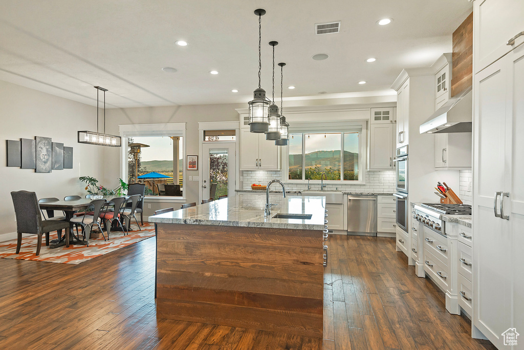 Kitchen featuring appliances with stainless steel finishes, a sink, recessed lighting, light stone countertops, and backsplash