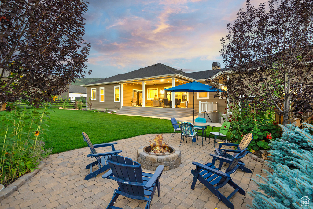 Back of house at dusk featuring a fire pit and a patio