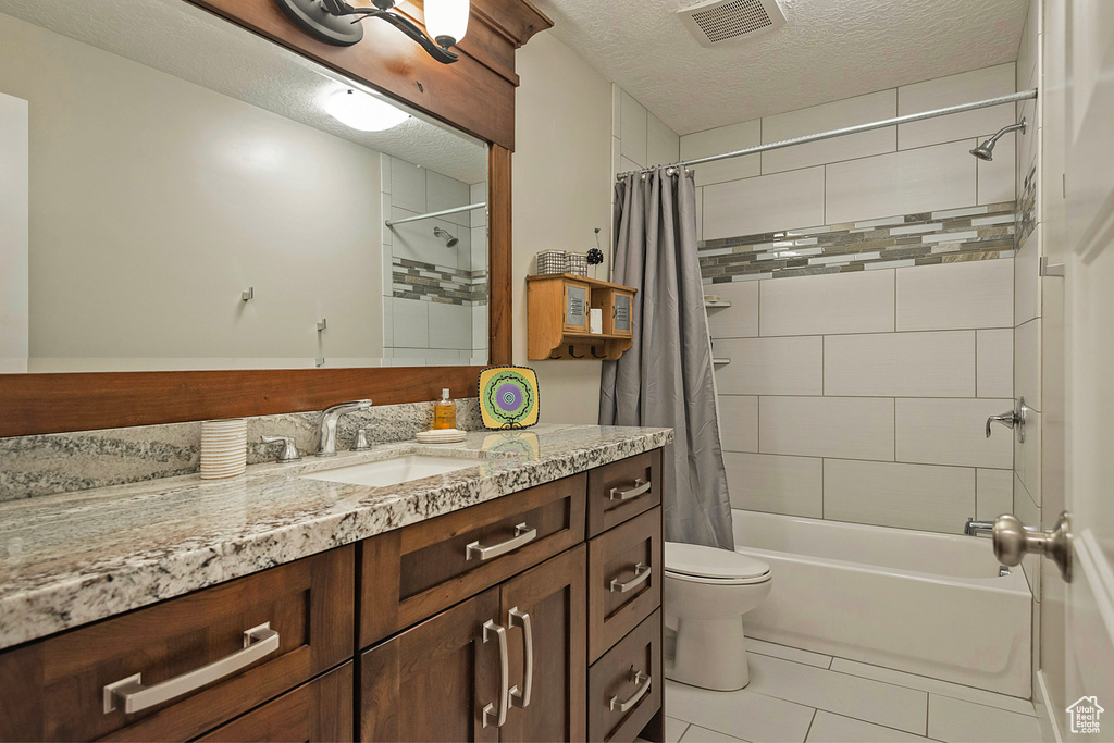 Bathroom with vanity, shower / bath combo, tile patterned flooring, a textured ceiling, and toilet