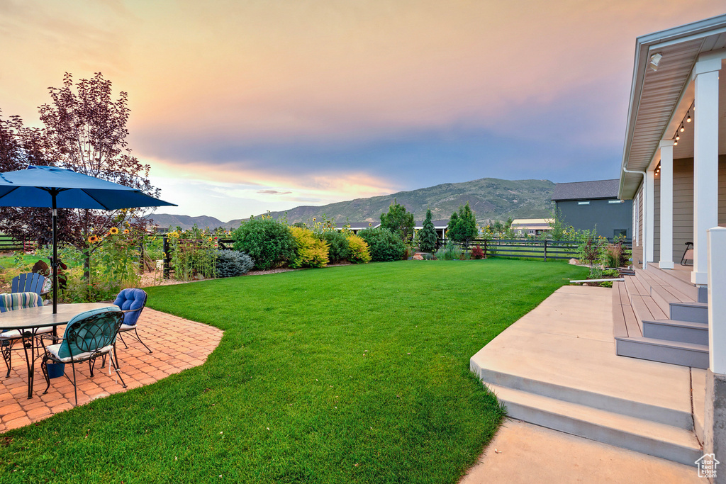 Yard at dusk with a patio area and a mountain view