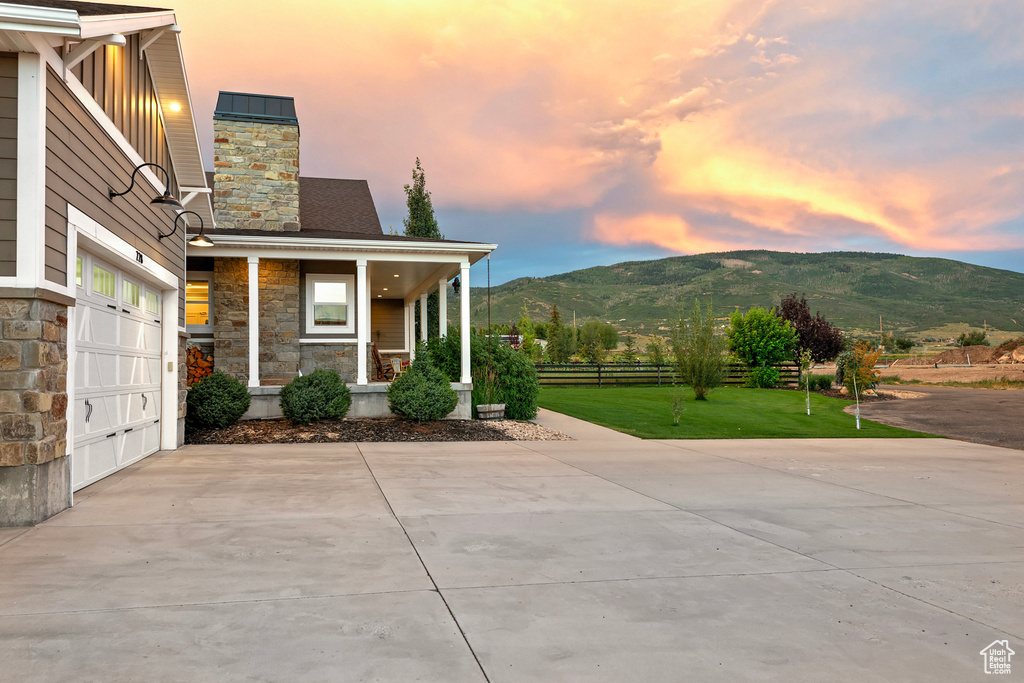 Covered porch featuring concrete driveway, a garage, and a mountain view