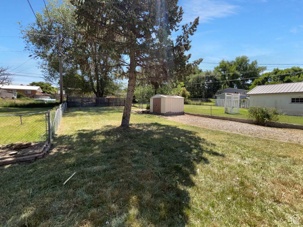 Fenced backyard featuring a storage unit