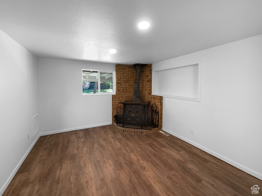 Unfurnished living room featuring a wood stove, wood finished floors, and recessed lighting