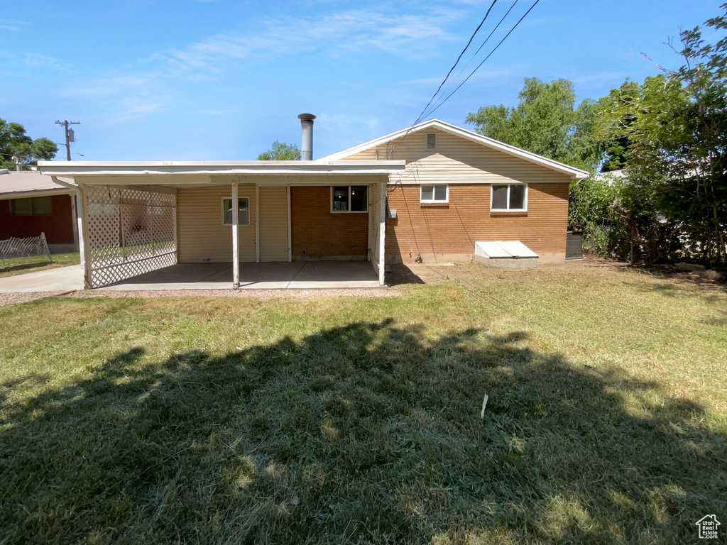 Back of property featuring a yard, a carport, and brick siding