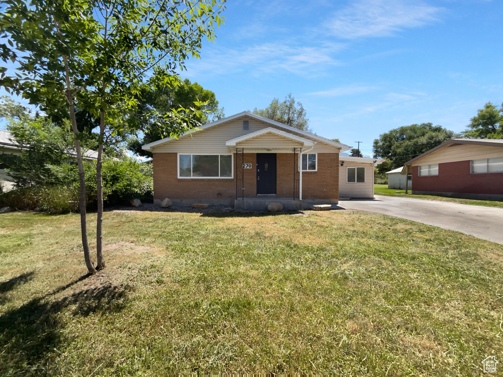 View of front of house with brick siding, driveway, and a front lawn