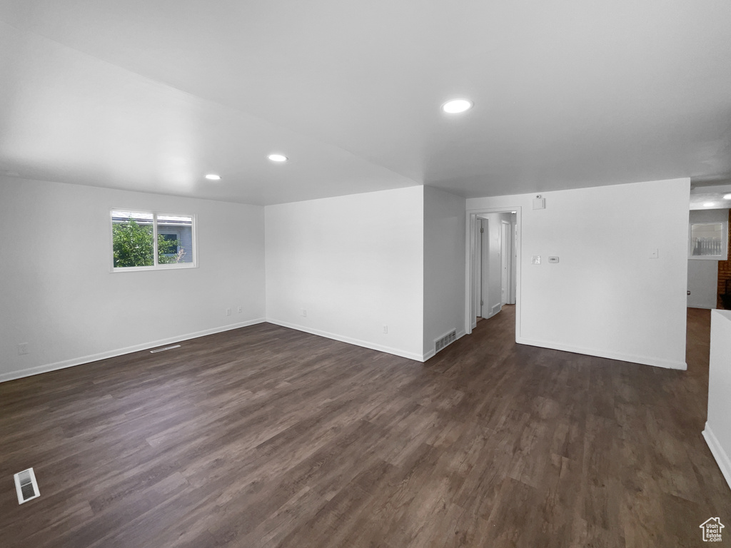 Empty room with dark wood-type flooring and recessed lighting