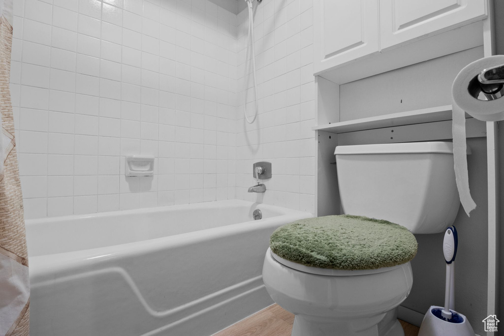 Bathroom with shower / washtub combination and wood finished floors