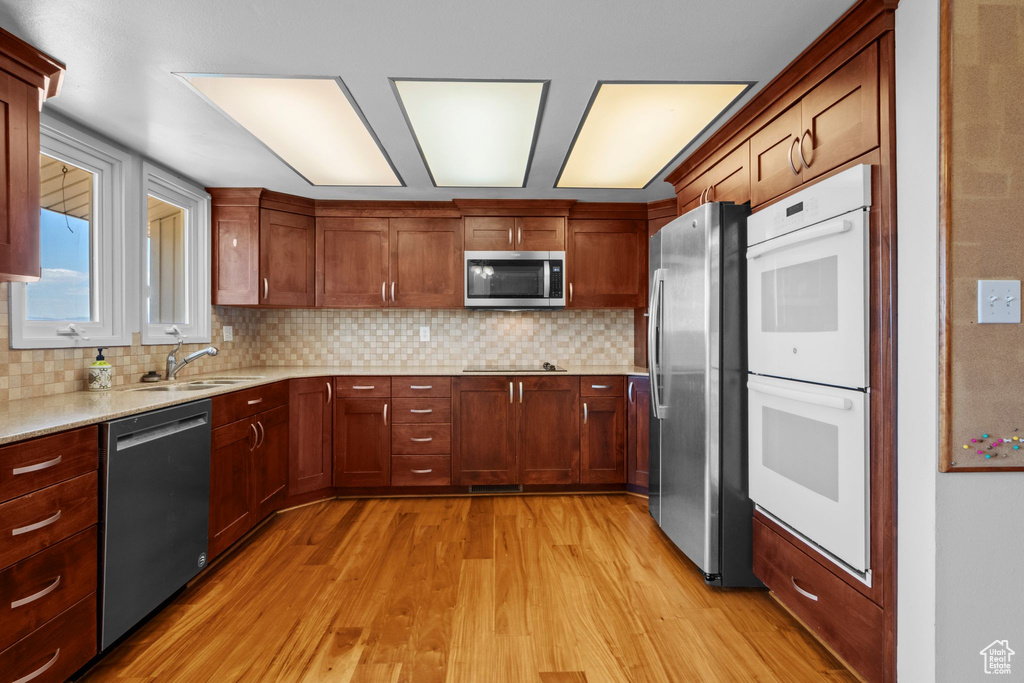 Kitchen with stainless steel appliances, light wood finished floors, and tasteful backsplash