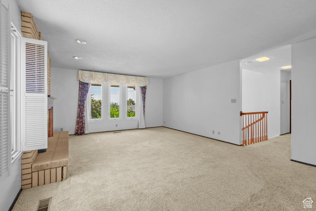 Empty room featuring carpet flooring and a textured ceiling