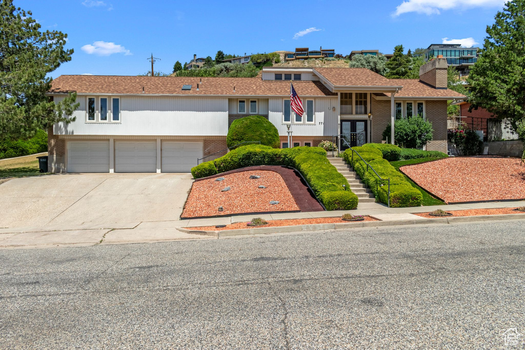 View of front of home featuring brick siding, driveway, stairway, and french doors