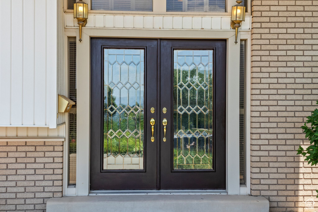 View of exterior entry featuring french doors, brick siding, and board and batten siding