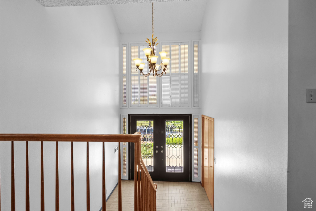Foyer entrance featuring a chandelier, french doors, plenty of natural light, and high vaulted ceiling