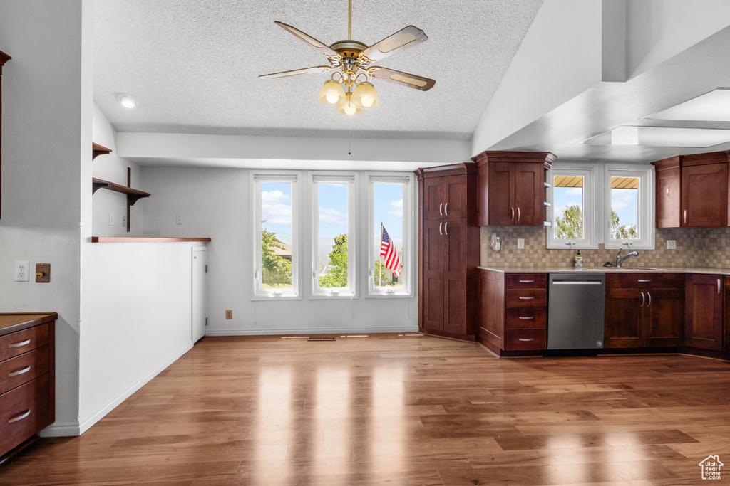 Kitchen featuring stainless steel dishwasher, a textured ceiling, a ceiling fan, healthy amount of natural light, and wood finished floors