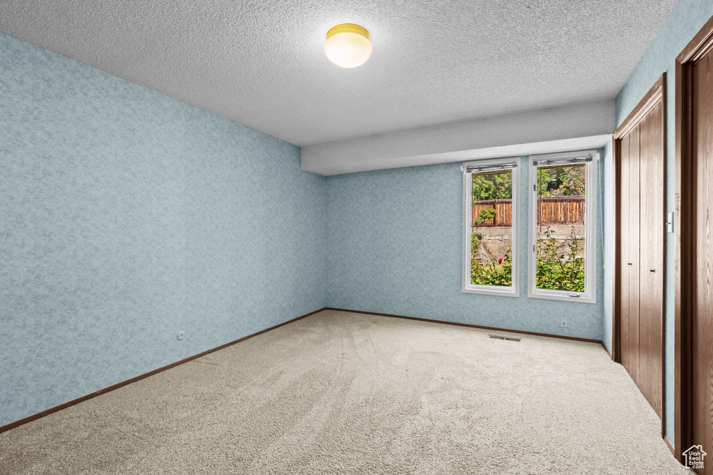 Unfurnished bedroom featuring a textured ceiling, carpet floors, and a closet