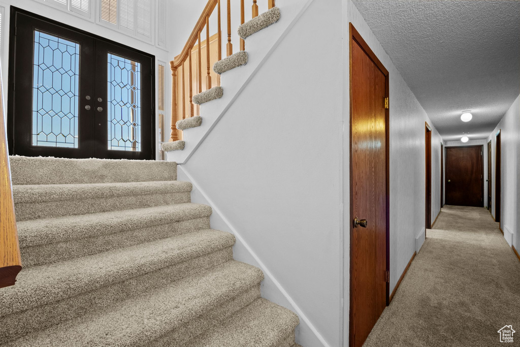 Stairway featuring carpet floors, a textured ceiling, and french doors