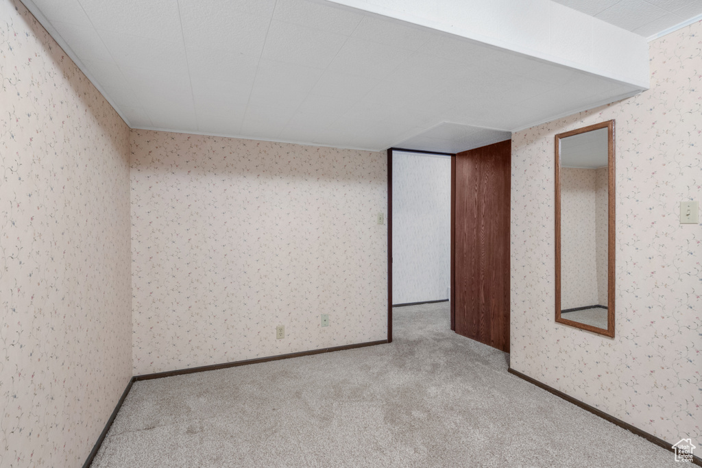 Unfurnished bedroom with wallpapered walls and carpet