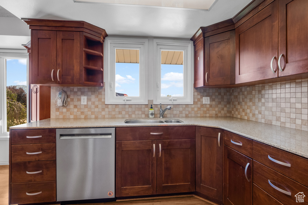 Kitchen featuring stainless steel dishwasher, backsplash, wood finished floors, light stone countertops, and open shelves