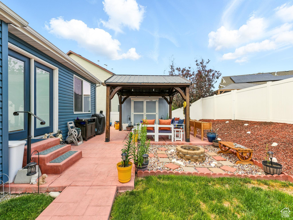 Fenced backyard featuring a gazebo, an outdoor living space with a fire pit, and a patio
