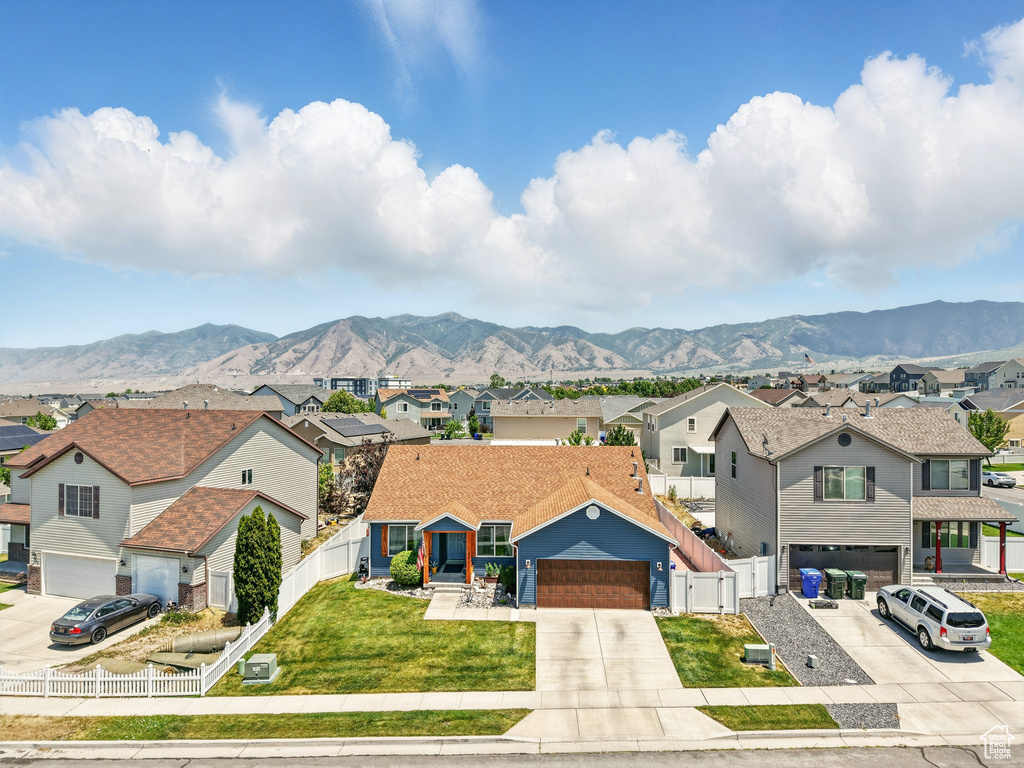 View of front facade with a residential view, a mountain view, concrete driveway, and a garage