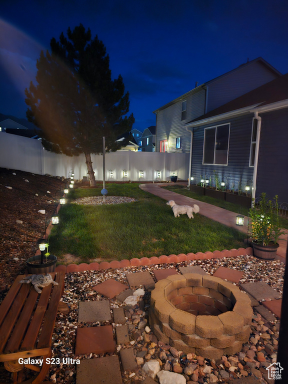 Yard at night with an outdoor fire pit and a fenced backyard