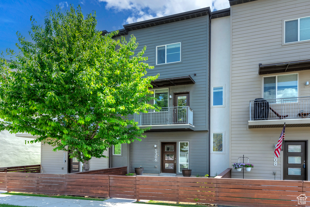 View of front of house with a fenced front yard and a balcony