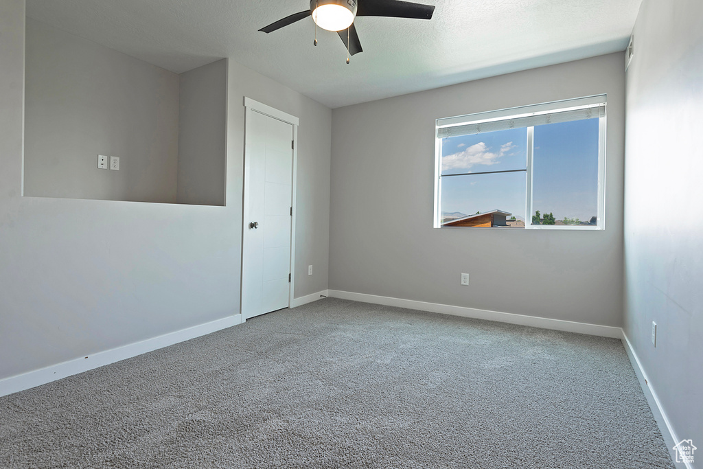 Empty room featuring ceiling fan and carpet floors