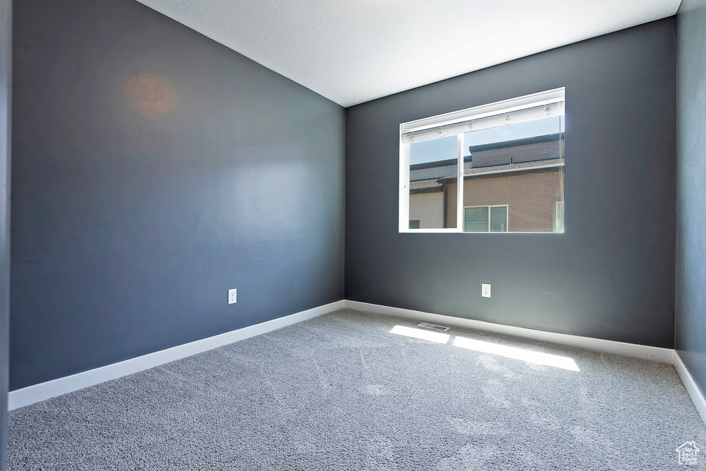 Carpeted empty room featuring lofted ceiling and baseboards