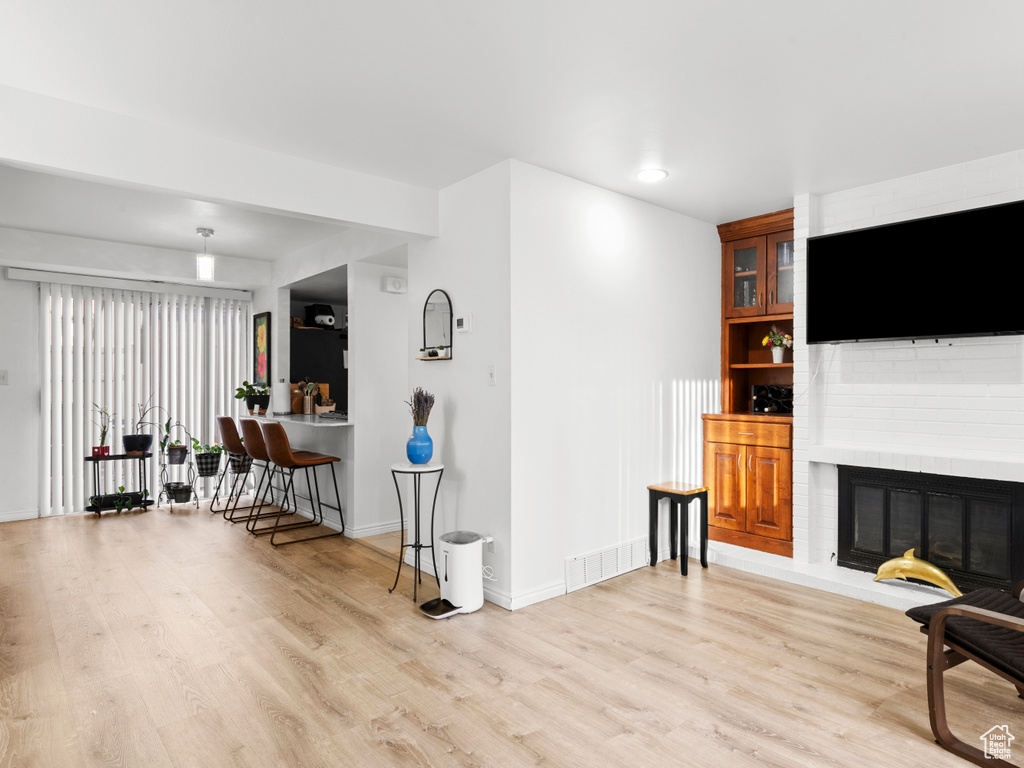Living room featuring light wood-style floors, a fireplace, and recessed lighting