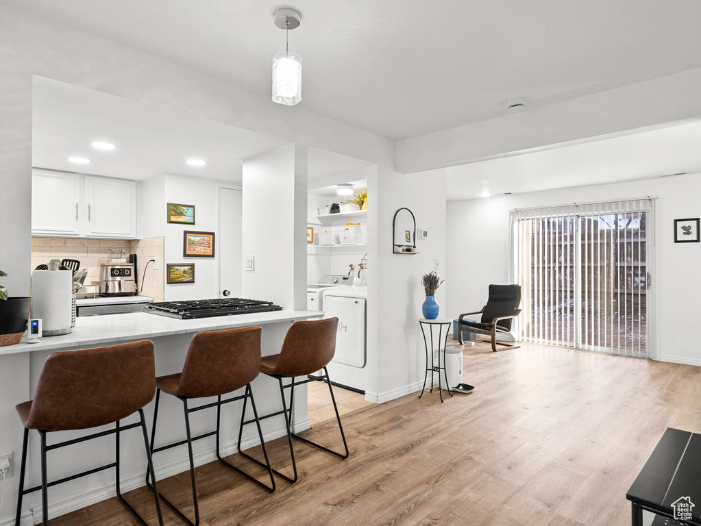 Kitchen with a breakfast bar, light wood finished floors, light countertops, independent washer and dryer, and recessed lighting