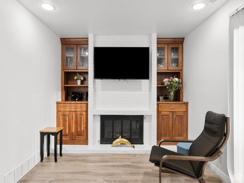 Living area with a fireplace, light wood-style floors, and recessed lighting