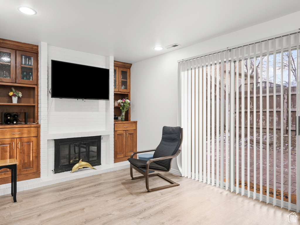 Living area with wood finished floors, a brick fireplace, and recessed lighting