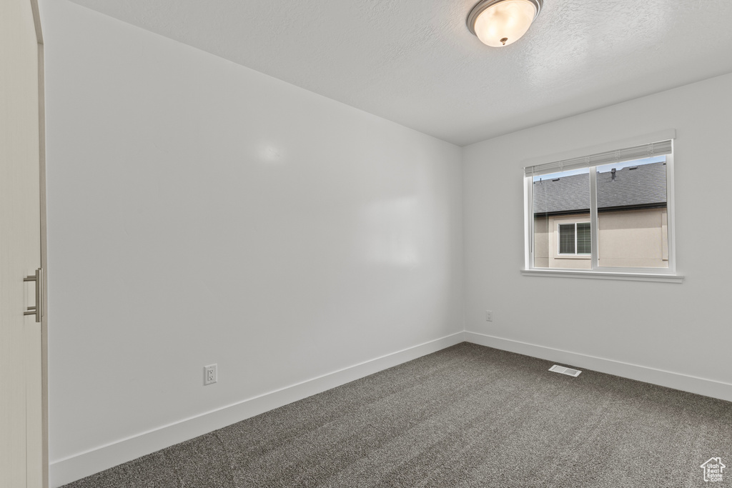 Spare room with baseboards and dark carpet