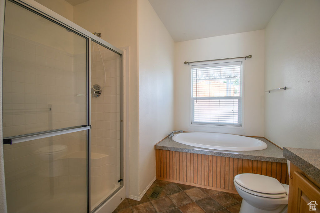 Full bath featuring a bath, a shower stall, stone finish flooring, vanity, and vaulted ceiling