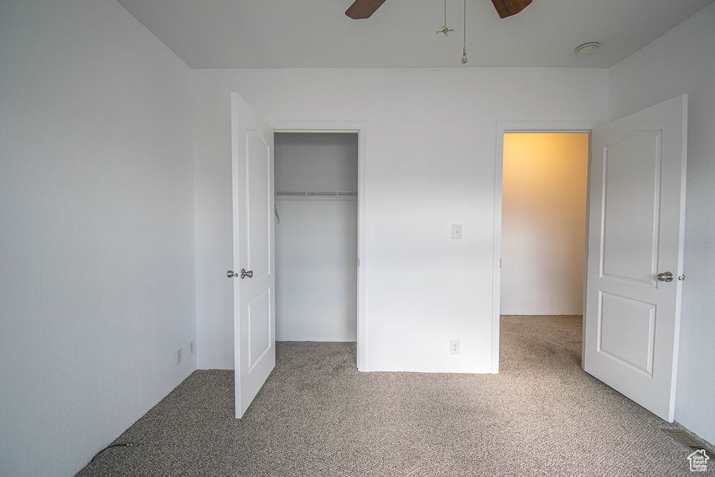 Unfurnished bedroom featuring carpet flooring, a closet, and a ceiling fan
