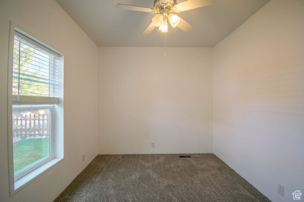 Empty room with healthy amount of natural light, carpet, and a ceiling fan