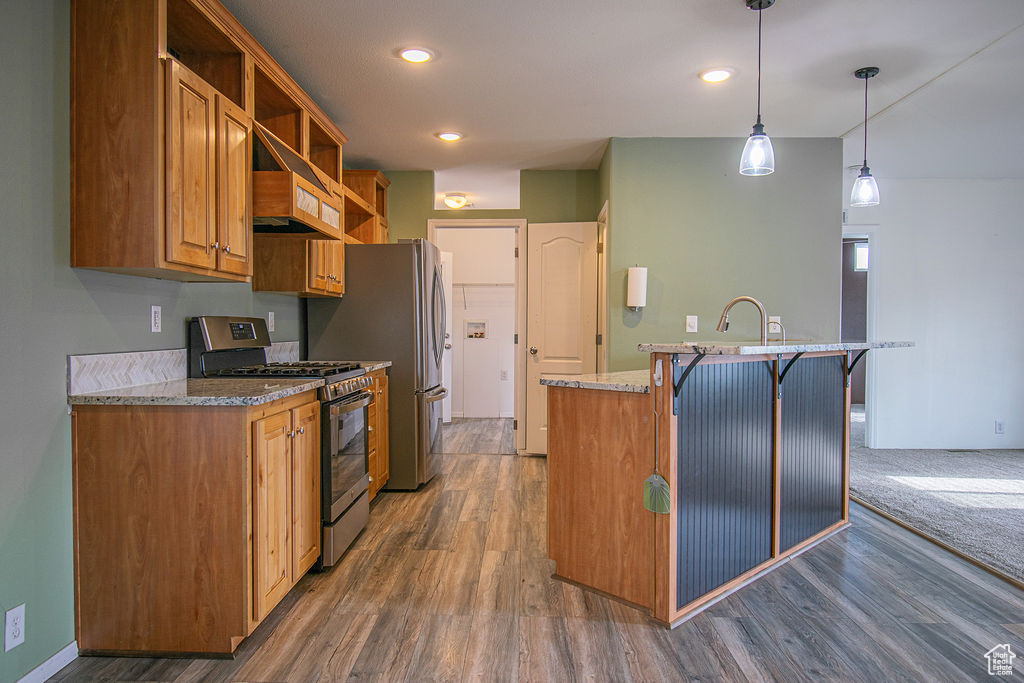 Kitchen with stainless steel appliances, open shelves, custom exhaust hood, dark wood-type flooring, and a kitchen island with sink