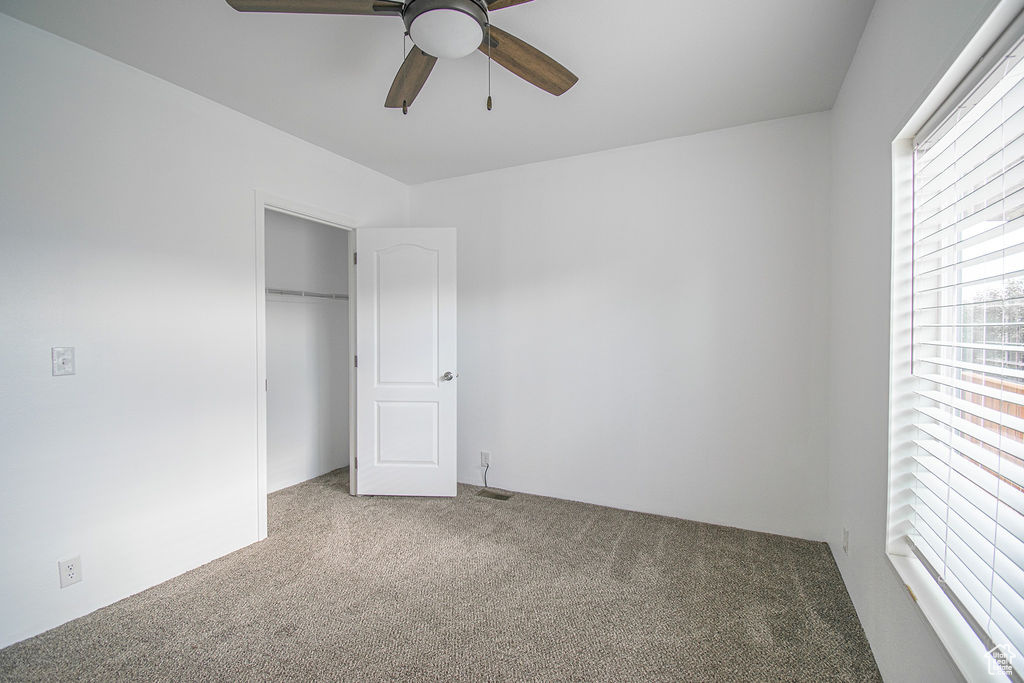 Unfurnished bedroom featuring carpet floors, a closet, and a ceiling fan