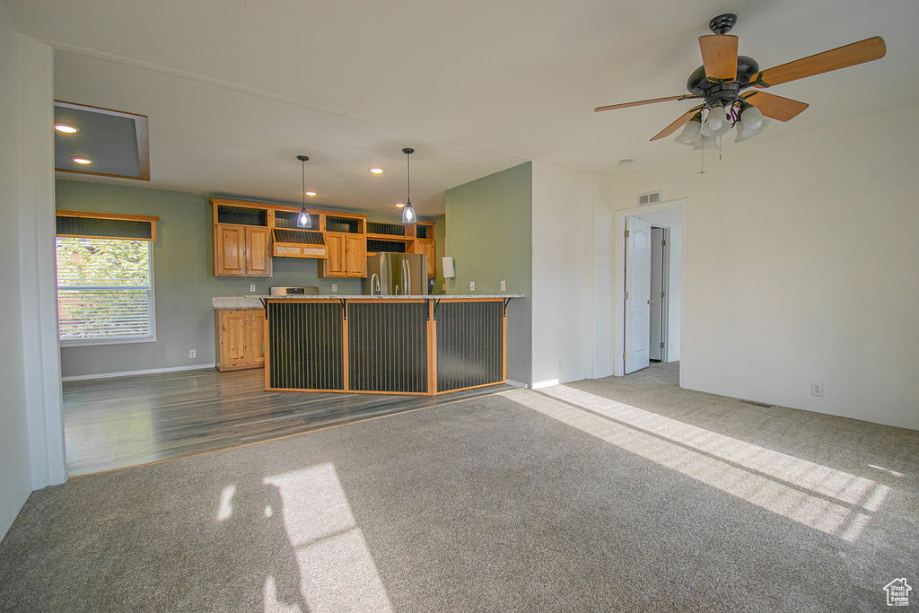 Kitchen with freestanding refrigerator, dark colored carpet, recessed lighting, ceiling fan, and pendant lighting