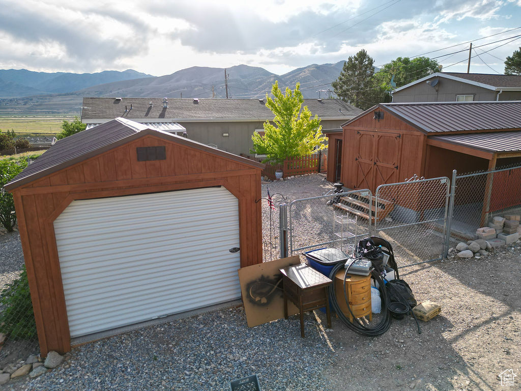View of outbuilding with a mountain view, a gate, and driveway
