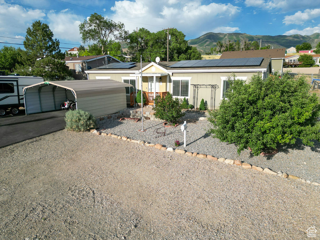 Ranch-style house with a mountain view, a detached carport, and roof mounted solar panels